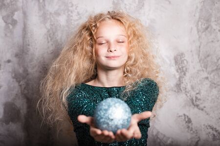 Merry Christmas and happy new year! happy girl with big ball toy in hands looks very pleased with closed eyes. Close portraitの写真素材