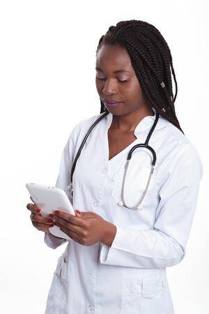 Female american african doctor, nurse woman wearing medical coat with stethoscope using tablet. Happy excited for success medical worker posing on light backgroundの写真素材