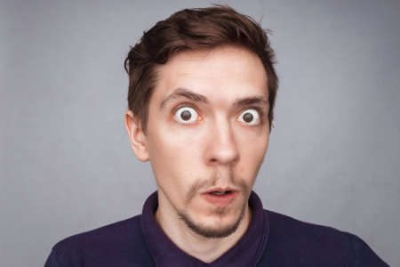 Emotions concept. Portrait of shocked male with small beard says wow, looks bugged eyes and rounded mouth, being amazed to see something unexpected. Terrified guy with surprised expression.の写真素材