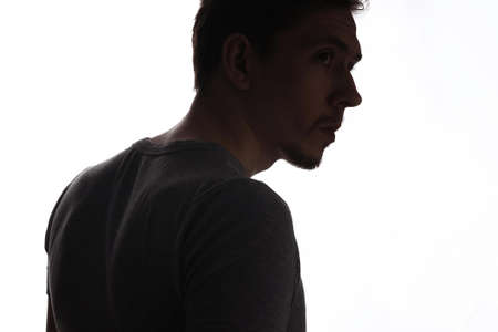 Portrait of a sensual young model in unlabeled gray t-shirt posing on white background. Serious man with small beard close-up portraitの写真素材