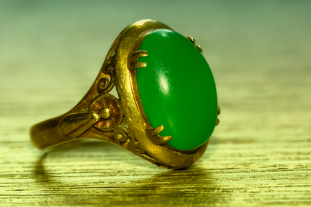 Green jade and gold ring on woodの写真素材