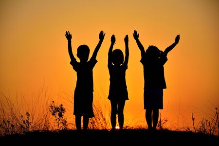 Silhouette of children who are friends at sunset.の写真素材