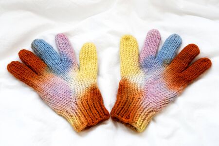 Christmas rainbow knitted mittens on white background.の写真素材