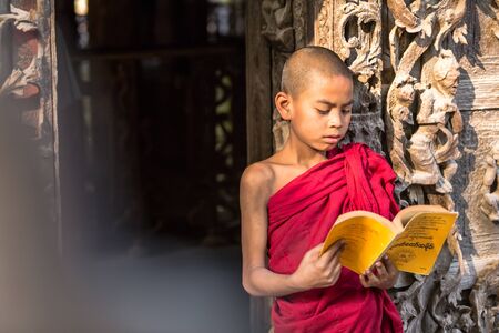 MANDALAY,MYANMAR-FEB 18 : Young monks standing and reading at Shwenandaw Monastery is built in the traditional Burmese architectural style on February 18,2015 in Mandalay,Myanmar.のeditorial素材