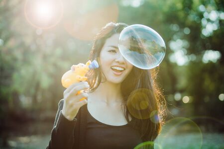 Beautiful young woman playing bubble in sunlight. Vintage film color filtered.