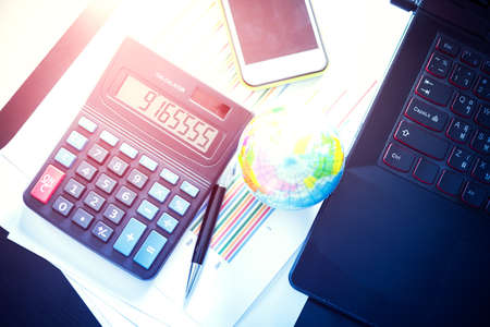 Graphs, charts, pen, calculator and mobile phone, business table. The workplace of business people. Vintage color filtered.の写真素材