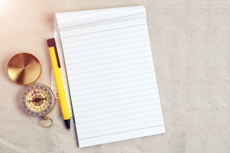 Compass, pen and notebook on blank paper, travel accessories concept in vintage color filtered.の写真素材