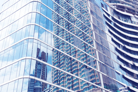 Glass of modern tower with sky reflection for business background.