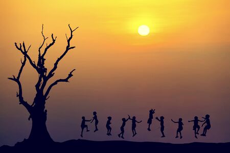 Silhouette of happy childrens jumping at sunset timeの写真素材