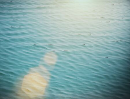 Soft focus of blue water wave with flare. Vintage filtered nature background.