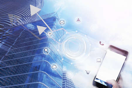 Businessman holding smartphone with business icon and high building in background. Business...