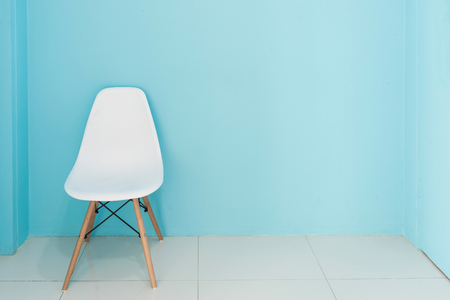 Modern white chair in a living room with blue wall with empty space for interior decorating or copyspace background.の写真素材