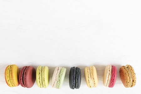 Colorful macaroons in a raw on white background. Sweet desert with free copy space for text.