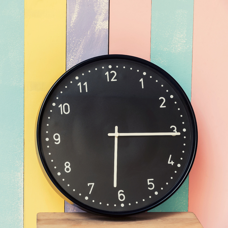 Closeup clock for decorate on wood desk and pastel wall textured background with free copy space for...