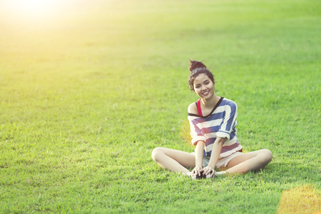 Happy young woman relax and smiling on green grass with sunrise in morning. Happy life lifestyle. Good healthy concept.の写真素材