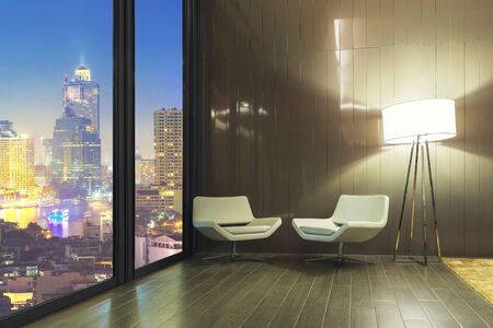 Interior of white sofa set with lamp in resting room with cityscape night view outside the window.の写真素材