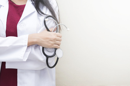 Healthcare background concept. Closeup doctor holding stethoscope standing on white wall with empty space.の写真素材