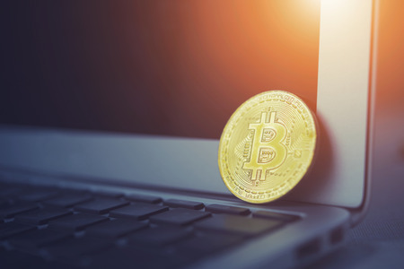 Bitcoin concept. Golden bitcoin put on laptop keyboard with empty screen with light. Picture for add text message. Backdrop for design art work.の写真素材