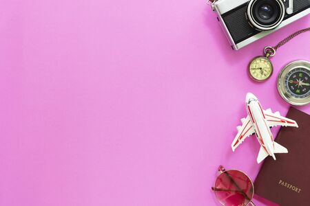 Travel and summer times concept. Flat lay of accessories, passport, sunglasses, compass, watch, airplane model and camera on pink background.の写真素材
