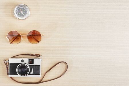 Old film camera , sunglasses and compass on wood table with free space for text. Travel and photography background concept. Happy vacation lifestyle.の写真素材