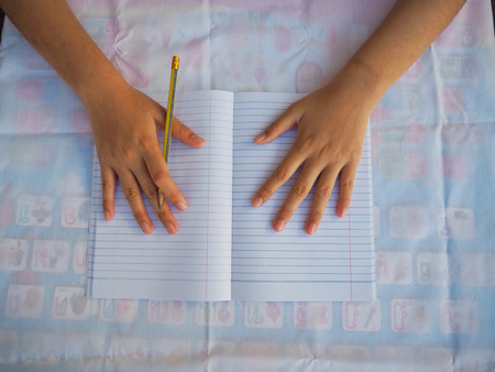 Student hand Write a book with a pencil.