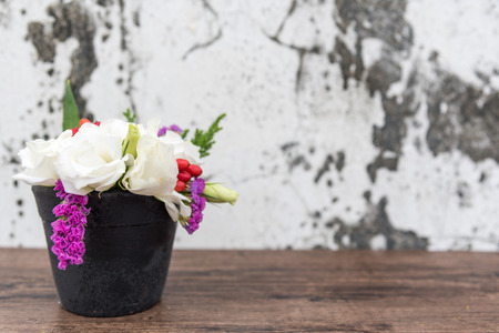 Colorful flowers are made up of white Lisianthus flowers and purple statice in black pots, with old concrete floors as backgrounds. represents the freshness of spring.の写真素材