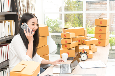 Asian business woman selling online marketing, shipping concept, startup small business working with computer at workplace. seller check product order and inventory, packing for delivery to customer.の写真素材