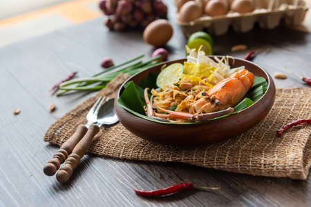 Pad Thai with fresh shrimp on a wooden table Pad Thai is a delicious Thai street food. And popular people around the worldの写真素材