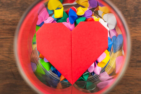 Colorful origami heart in glass on wooden table の写真素材