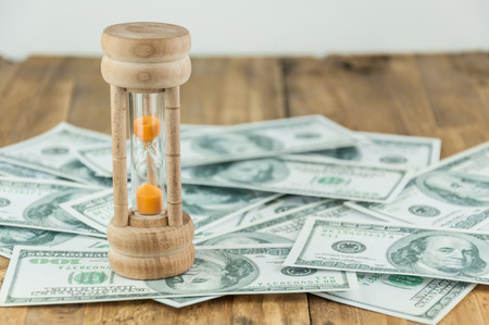 wooden hourglass on money background concept for Savings