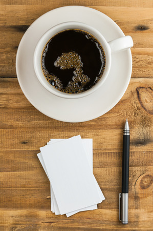 business card with pen and coffee cup on wooden tableの写真素材