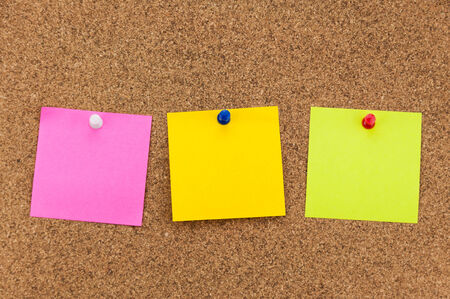 three blank sticky notes on corkboard background