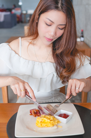 Asian woman eating breakfastの写真素材