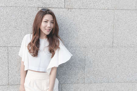 Young Asian girl smile against concrete wall backgroundの写真素材