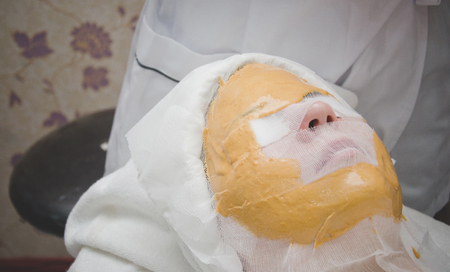 a woman has to mark gold her face in the spa shop, thailandの写真素材