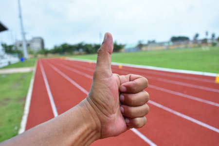 Hand of people with thumb up isolated with running track background. People thumb up about confirm about sports and exercise help to care healthy.の写真素材