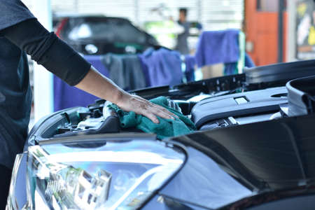 The worker of car care shop holds microfiber in hand and polishes the car. Selective focus