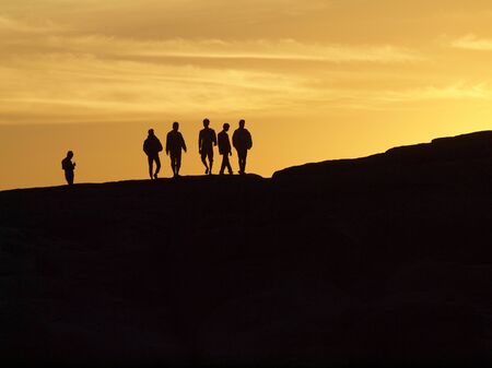 People standing in sunset on the cliffの写真素材