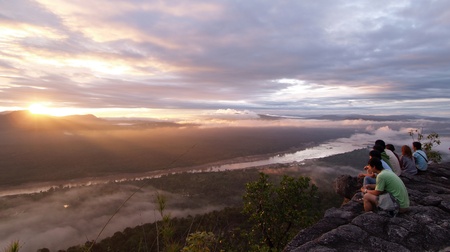 People sitting and looking sunrise at the canyon over the riverのeditorial素材