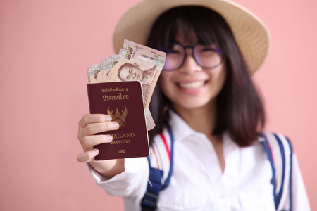 Asian girl holding passport and banknote to travelの写真素材