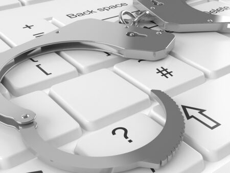 Handcuffs lying on computer keyboardの写真素材