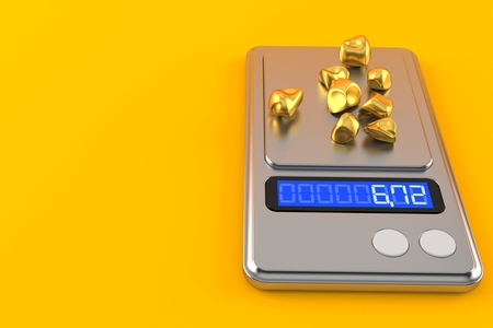 Gold nuggets on weight scale isolated on orange backgroundの写真素材