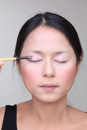 Beautiful asian woman doing make-up on face with cosmetic brush の写真素材