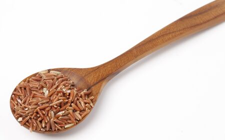 Raw and uncooked rice in wooden spoon over white backgroundの写真素材