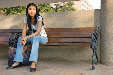 Young Thai woman waiting on a park benchの写真素材