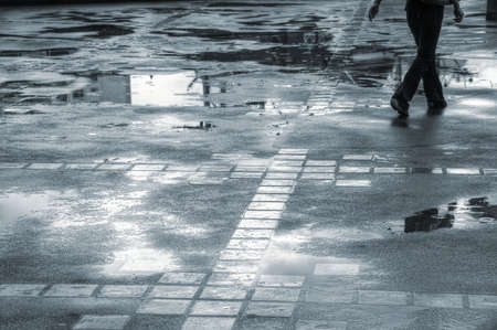Person walking through puddles on a wet sidewalkの写真素材