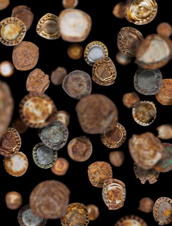 Lots of old rusty bottle caps falling like rain on a black backgroundの写真素材