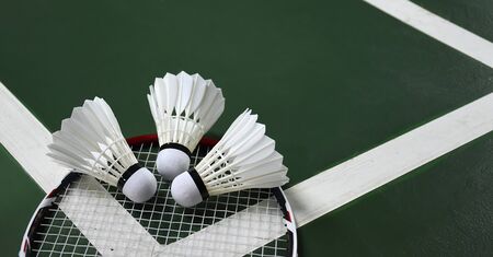 Badminton racket and badminton feather shuttlecocks on court.