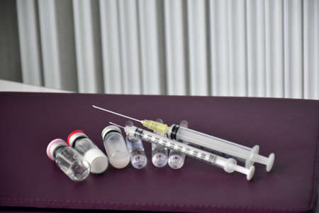 Medical equipments, injections, insulin, serum and vaccine bottles, on brown leather cover taplet of...