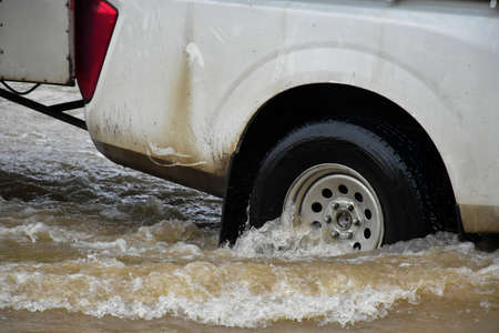 Vehicles are passing the road which fulled of floodwater. Concept for car insurance, safty and...